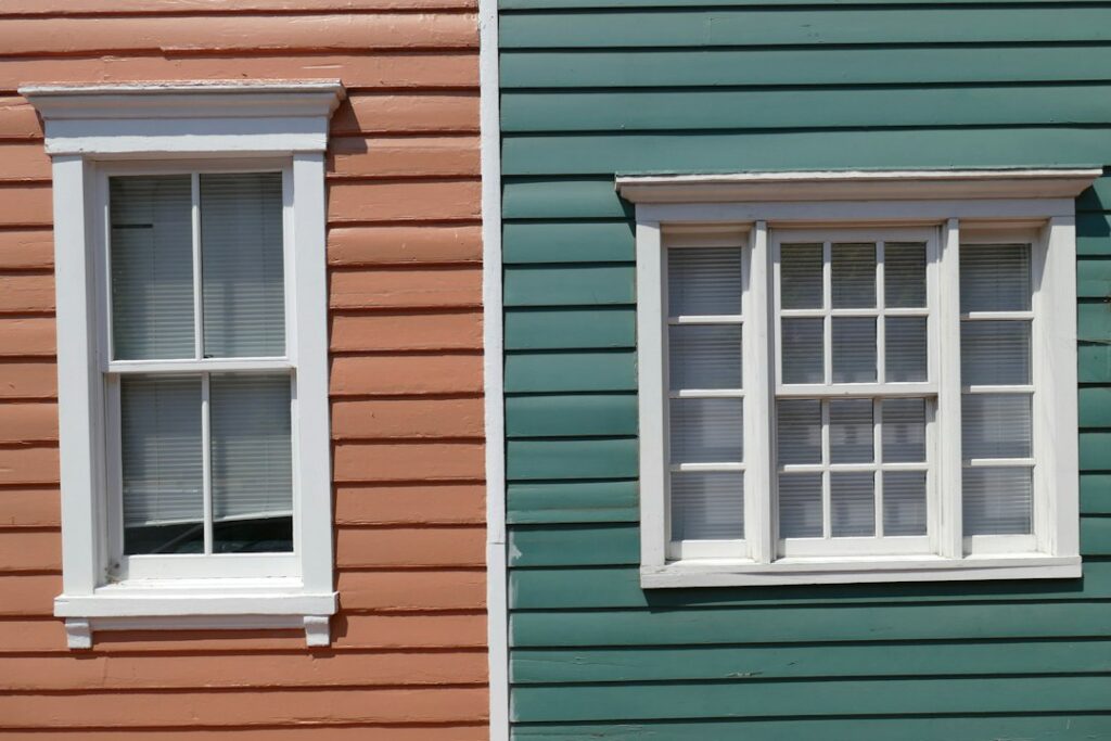 Homeowners repair a historic wood window beside original trim, tools, paint, and restored plaster walls.