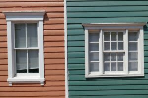 Homeowners repair a historic wood window beside original trim, tools, paint, and restored plaster walls.
