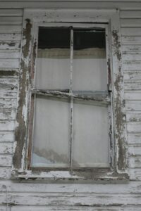 Craftsperson repairing a wood sash window beside original trim in an older home.