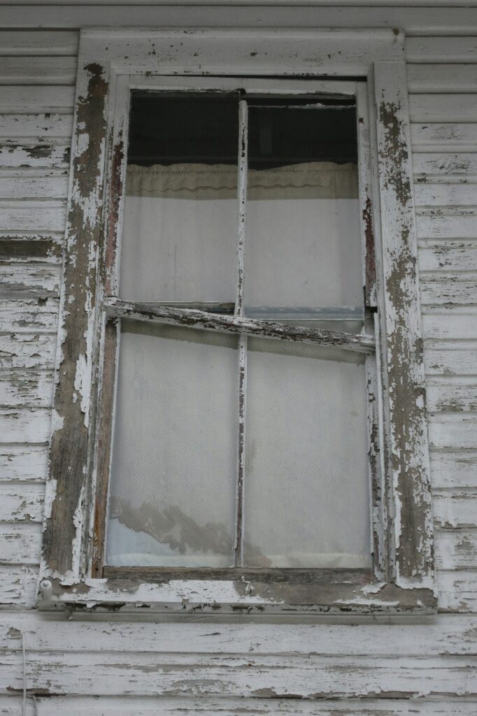 Craftsperson repairing a wood sash window beside original trim in an older home.