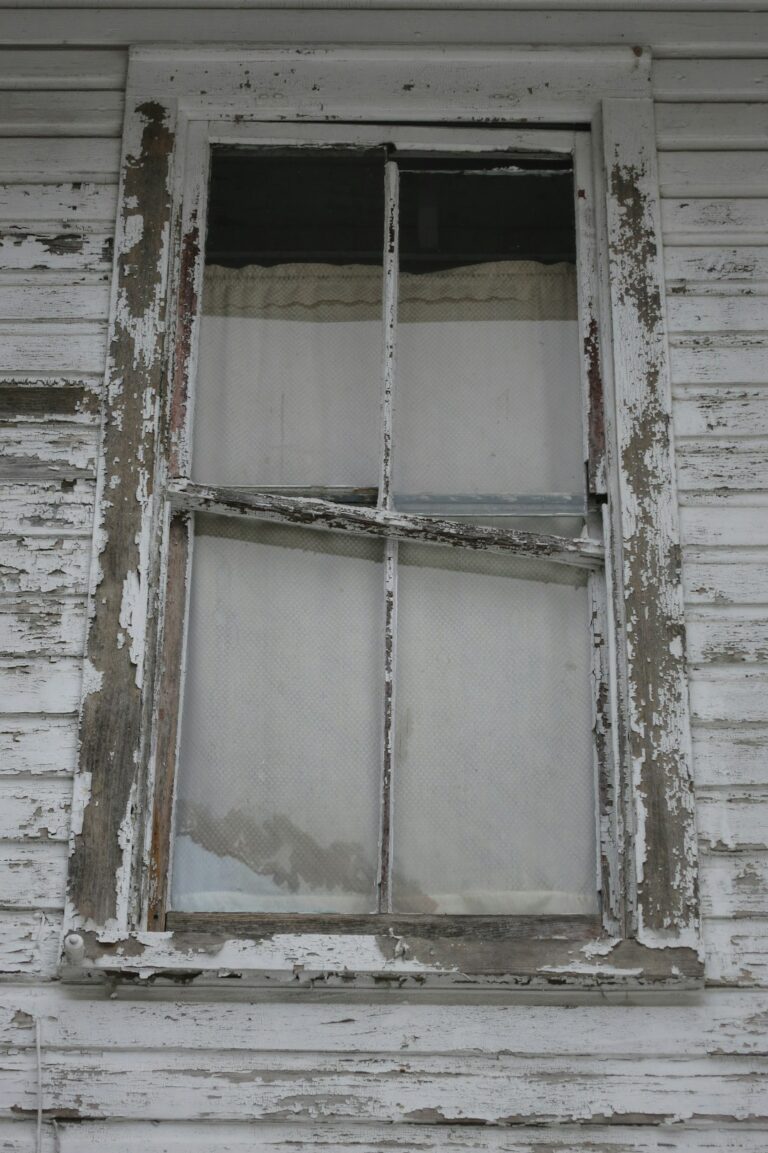 Craftsperson repairing a wood sash window beside original trim in an older home.